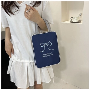 Detail of navy canvas laptop sleeve featuring blue butterfly embroidery and grey handles