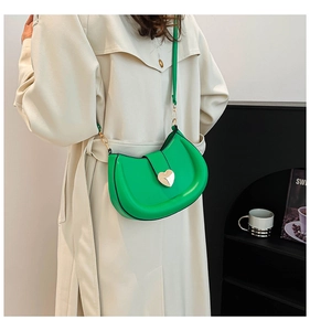 Détail d'un sac demi-lune vert avec fermoir cœur doré et finition en cuir lisse brillant