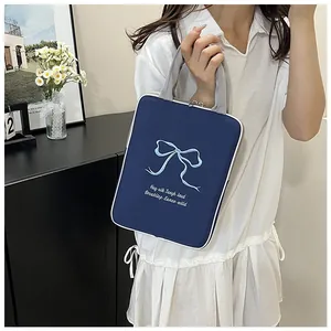 Detailed embroidery of light blue bow and cursive text on a dark blue laptop bag