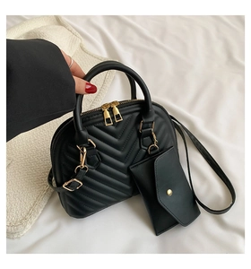 Détail du sac à main noir matelassé en V, avec quincaillerie dorée et pendentif assorti