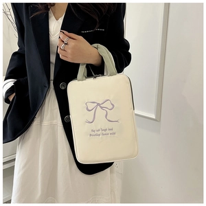 Detail of embroidered purple bow and artistic lettering on a cream laptop tote bag