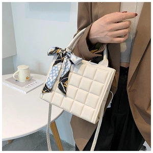 Detailed shot of quilted cream tote bag with silk scarf on the round handle