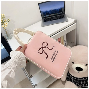 Pink laptop sleeve with butterfly embroidery and white handles shown in home office