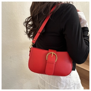 Gros plan du sac porté épaule rouge vif avec boucle dorée rétro porté par le mannequin