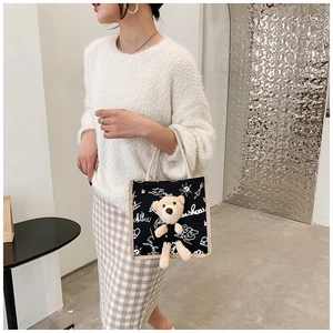 Detail of black canvas tote bag featuring a 3D plush teddy bear and white graffiti prints