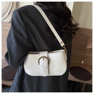 Détail du sac à bandoulière crème avec une boucle ronde en métal et un cuir lisse rétro