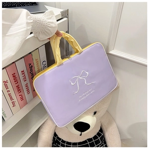 Detailed embroidery on purple laptop sleeve with yellow handles and bow design