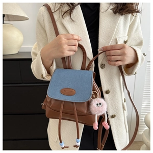 Close-up of brown leather and denim crossbody bag featuring a pink monster charm
