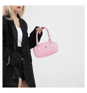 Detailed view of pink textured fabric bowling bag with gold logo on black blazer background