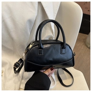Close-up of black leather shell bag with embossed fashion text and gold hardware