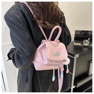Pink mini leather backpack detail with plush monster charm and silver brand plate