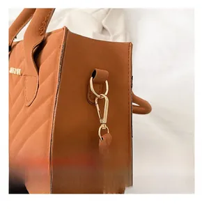 Detailed side view of brown chevron quilted handbag with gold metal hardware D-rings