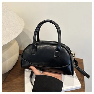 Detail of black semi-circular handbag featuring embossed FASHION text and dual handles