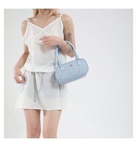 Close-up of light blue denim bowling bag with gold logo and leather top handle detail