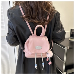 Detail of a mini pink backpack with silver metal logo and a fluffy plush eye keychain