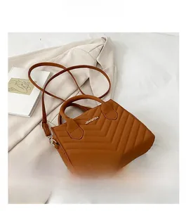 Detail of tan quilted PU leather bag with V-shaped stitching and metallic brand logo