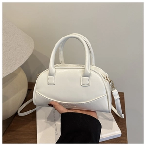 Close-up of a white mini shell bag with FASHION engraving and dual top handles