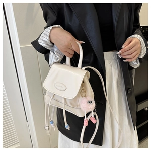 Detail of white mini leather backpack featuring drawstring closure and pink plush charm