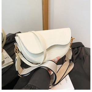 Detail of off-white saddle bag with wide canvas strap and metal buckle closure