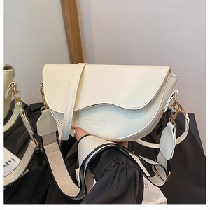 Detail of cream white saddle bag with scalloped flap and dual interchangeable straps
