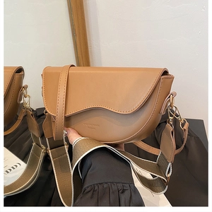 Detail of coffee brown leather saddle bag with wave flap and dual shoulder straps