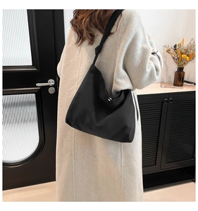 Detail of minimalist black large tote bag with decorative knot on shoulder strap