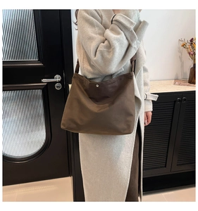 Close-up of the metal snap button on a dark brown canvas tote bag with drape