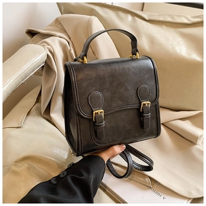 Detail of vintage black faux leather backpack with gold buckles and dual straps