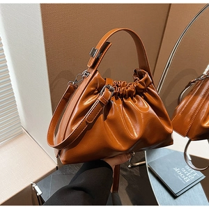 Détail d'un sac nuage plissé marron avec poignée à boucle métallique et fine bandoulière
