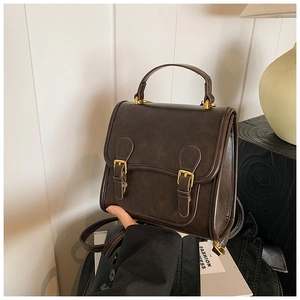 Detail of vintage brown faux leather backpack with gold buckles and top handle