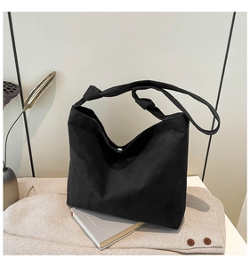 Detail of a large black suede tote bag with a unique knotted shoulder strap and slouchy design