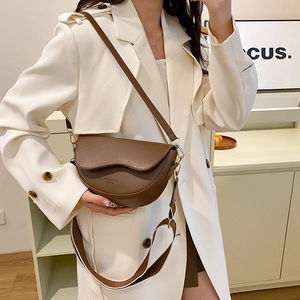 Minimalist brown saddle crossbody bag with wave flap design and gold hardware