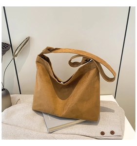 Detail of suede tote bag showing knot handle design and magnetic closure on textured fabric