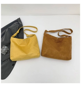 Flat lay of suede tote bags in yellow and brown with decorative knot straps and button