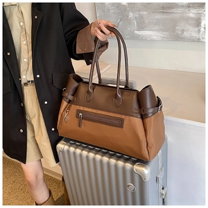 Detail of contrasting brown large tote bag placed on a silver suitcase for travel