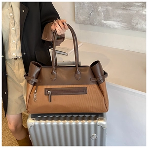 Close-up of contrast large tote bag on a suitcase showing brown leather and fabric details