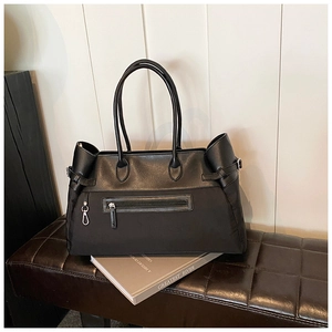 Close-up of black nylon and leather tote bag with front zipper and side buckle detail