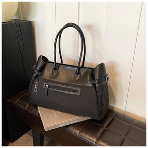 Detail of black tote bag with leather contrast and zipper pocket on a leather bench