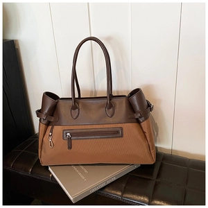 Detail of a large capacity two-tone tote bag with side buckles and front zipper pocket