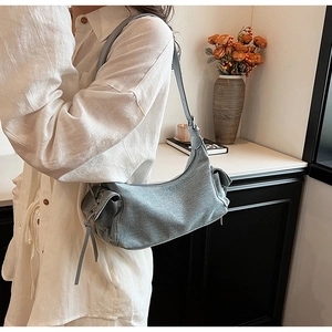 Detail of light blue underarm bag featuring side drawstring knot and adjustable strap