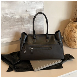 Detail of the black tote bag featuring a front zipper pocket and metal hook accents