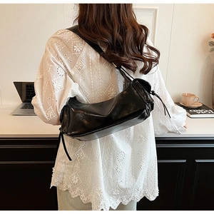 Close-up of black polished leather hobo bag with sleek tassels and glossy finish