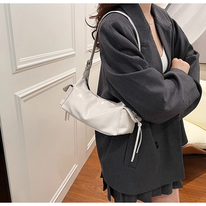 Detail of white PU leather underarm bag featuring side knot design and glossy texture