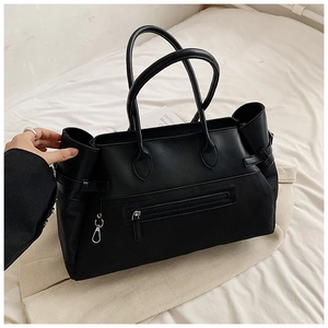 Detail view of a large black mixed-media tote bag with leather straps and zip pocket