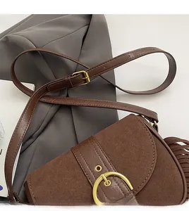 Detail of vintage brown saddle bag showing suede texture, fringe tassels, and brass buckle