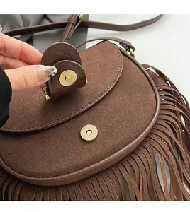 Detailed close-up of brown suede saddle bag showing the golden magnetic buckle closure