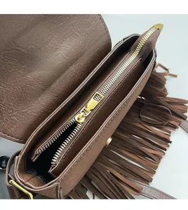 Detail of dark brown leather crossbody bag featuring smooth metal zipper and side tassels