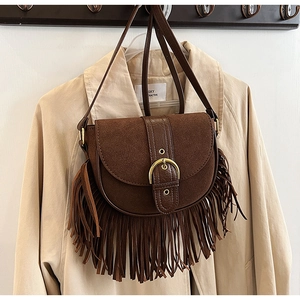 Close-up of vintage brown matte leather saddle bag with bohemian tassel fringe detail