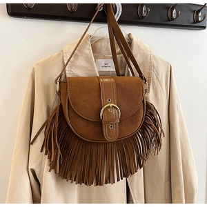 Detail of a brown fringe saddle bag with matte leather finish and golden buckle