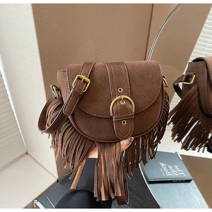 Detailed view of bohemian dark brown suede saddle bag with long fringe and metal buckle